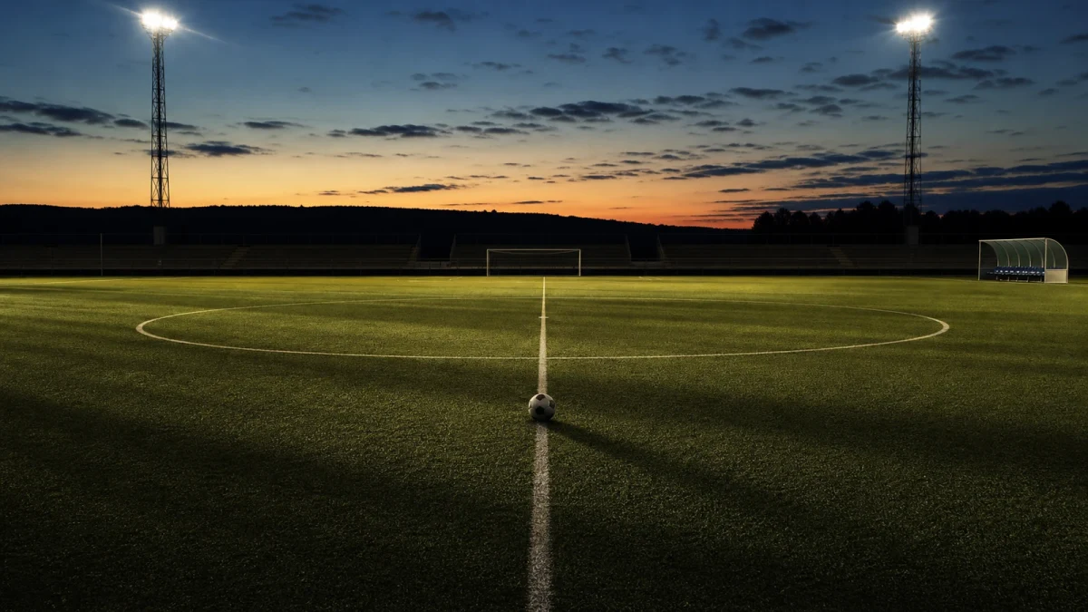 Fotboll på mittlinjen på en tom plan i skymningsljus